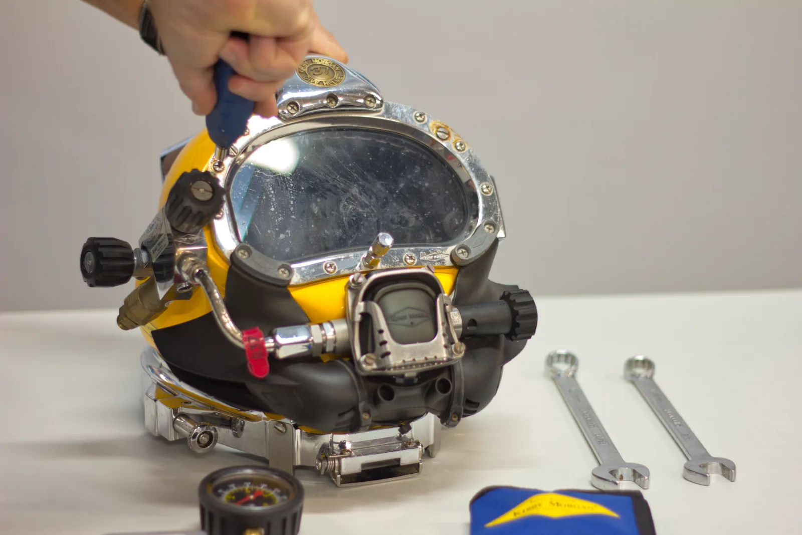 Instructor servicing a Kirby Morgan KM37 helmet with hand tools in the UTCSA workshop